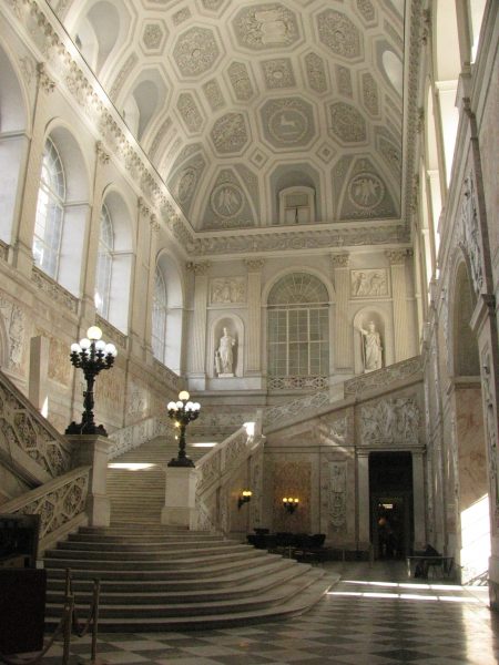 scalinata all'ingresso del palazzo bianca e luminosa, alle pareti bassorilievi e statue di marmo