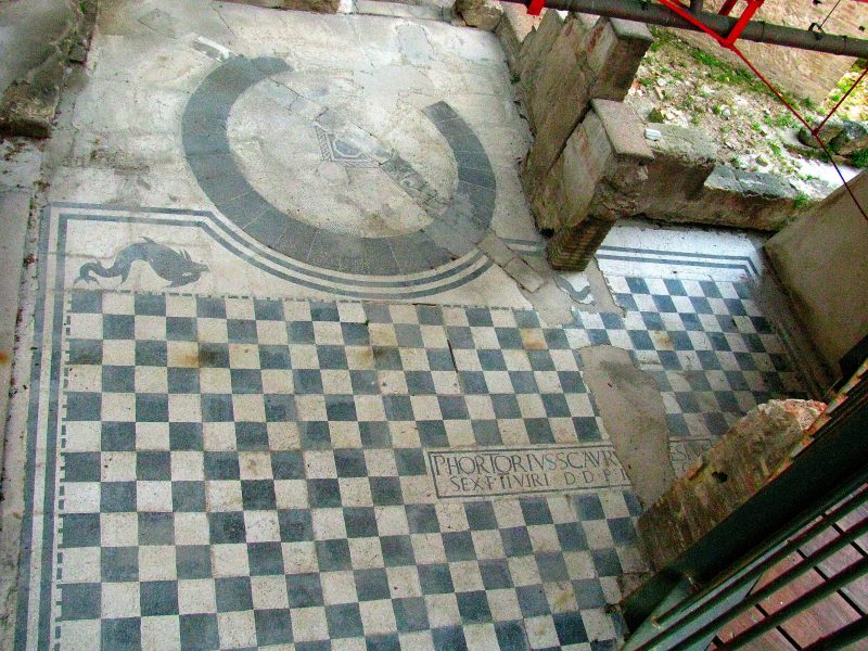pavimento dell'antico anfiteatro romano: scacchiera bianca e nera con alcune iscrizioni e la figura di un delfino