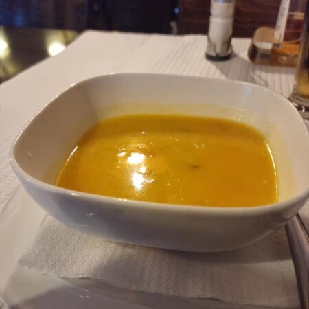 una ciotola di zuppa dal colore giallo aranciato e dalla consistenza densa